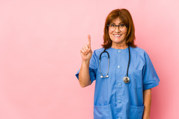 Middle age caucasian nurse woman isolated showing number one with finger.