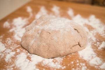 Homemade pizza dough close up on a wooden board with flour. Delicious typical italian recipe. Top view.