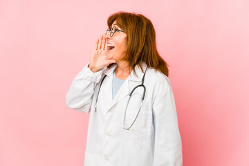 Middle age caucasian doctor woman isolated shouting and holding palm near opened mouth.