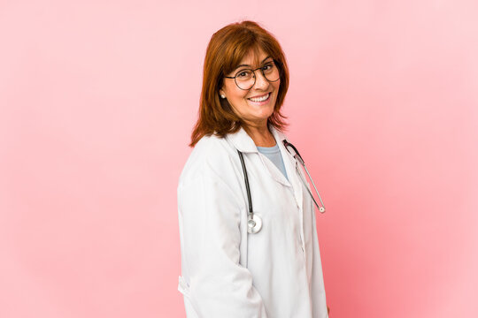 Middle age caucasian doctor woman isolated looks aside smiling, cheerful and pleasant.