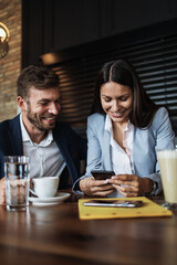 Happy couple man and woman sitting in modern cafe bar or restaurant and drinking coffee.