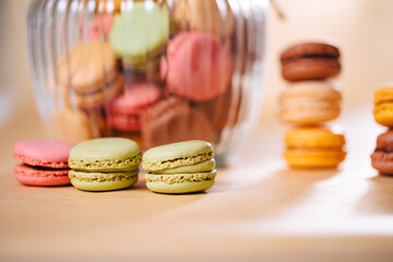 Macaroons of different colors in a glass container. Stacked macaroons