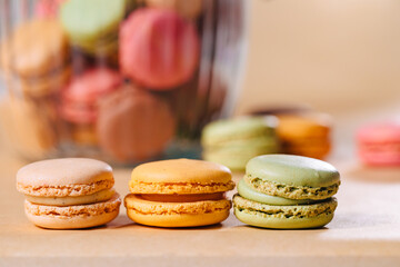 3 macarons stand next to each other on the table macarons in different colors: yellow, brown, green