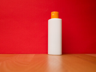 White tube bottle of shampoo, conditioner, hair rinse, mouthwash, on a red background.