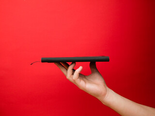 Hand of European men holding black note. Isolated on red background. Studio portrait.