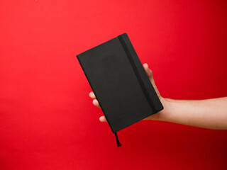 Hand of European men holding black note. Isolated on red background. Studio portrait.