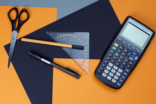 office supplies (pen, calculator, scissor) on a orange-black background