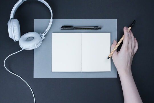 hand with pen, notebook and headphones with blank space
