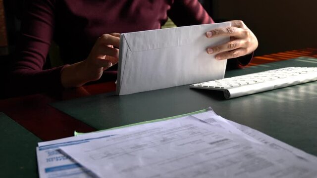 Woman goes through a stack of bills piling up. In debt or financial stress concept.
