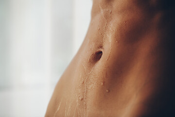 Fototapeta premium Close up of fit woman torso with sweat on skin after workout. Female with perfect abdomen muscles 