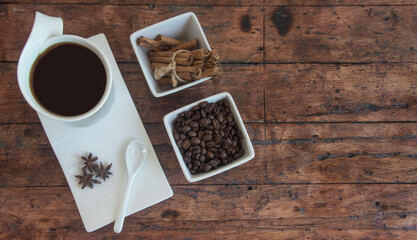 cup of coffee accompanied with cinnamon and coffee beans