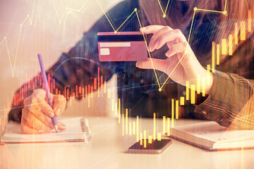 Double exposure of woman on-line shopping holding a credit card and financial graph drawing. Stock market E-commerce concept.