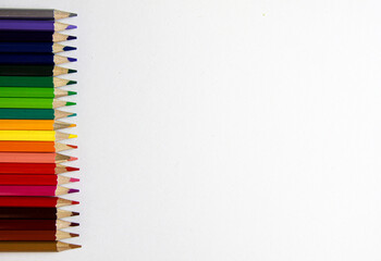colored pencils lie in a row on a white background