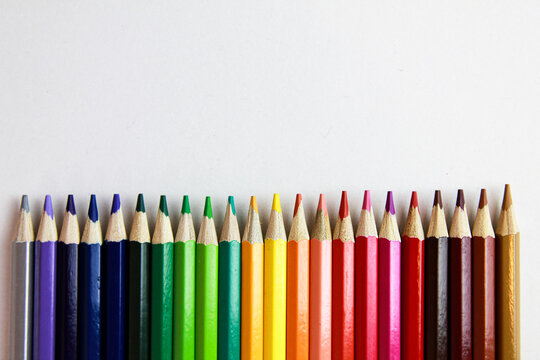 colored pencils lie in a row on a white background