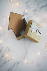 buying or investing in a new house, house icon inside of open present box surrounded by fairy lights