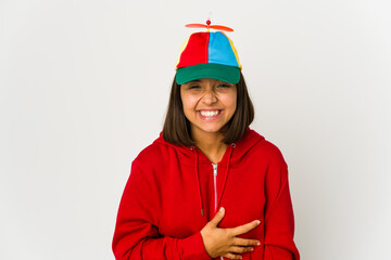 Young hispanic woman wearing a cap with propeller isolated laughing and having fun. © Asier