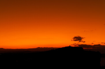 Fototapeta na wymiar orange sunset with mountain silhouette and a person