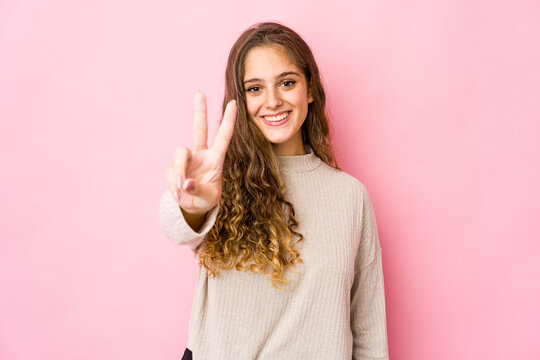 Young caucasian woman showing victory sign and smiling broadly.