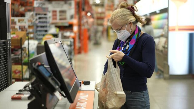 Closeup of woman wearing face mask looking at paint chips in a hardware store. Concept of coronavirus shopping experience.