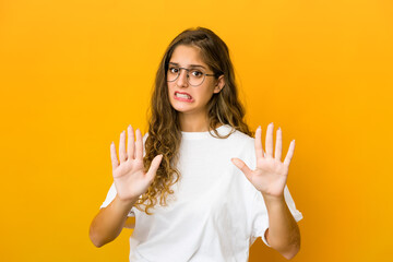 Young caucasian woman rejecting someone showing a gesture of disgust.