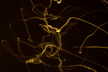 Yellow light streaks on a black background (long exposure).