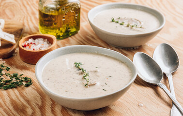 Mushroom cream soup in gray bowls with parsley on wooden background