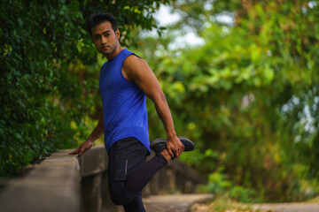 athletic man relax and leg stretching after jogging workout outdoors in park