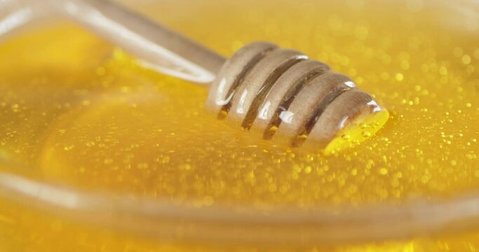 Fresh honey with a wooden spoon rotates. 