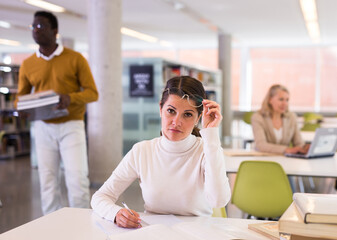 Obraz premium Portrait of positive woman with book in public library. High quality photo