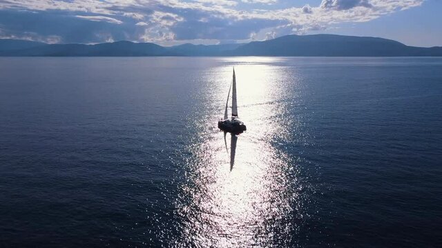 Beautiful white sailboat in open water on sunny weather, aerial view.