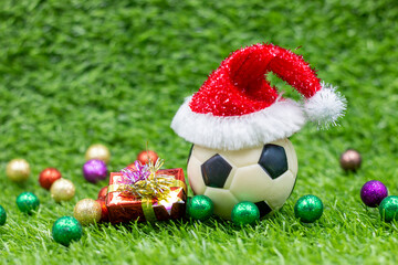 Soccer ball with Santa hat on green grass