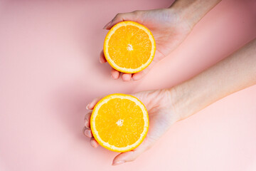 Two hands of woman holding a slice of orange.