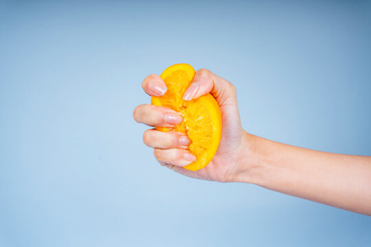Hand of woman squeeze slice of orange.