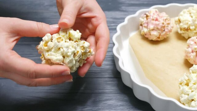 Woman taking popcorn ball from plate and breaking it apart, closeup