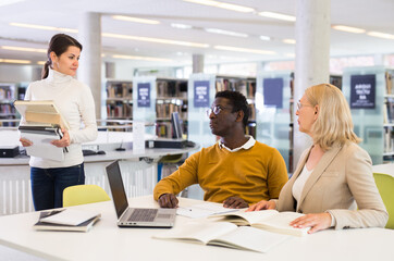 Fototapeta premium Teacher and adult students talking in the library. High quality photo