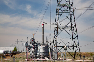 Electric transformer with isolators and pylons. Distributing substation Kegos. Blue sky with light clouds background.
