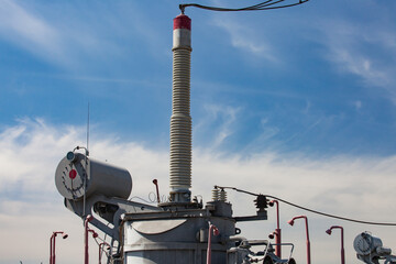 Electric transformer and ceramics isolators close-up. Distribution substation of electricity. Blue...