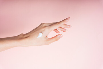 Hand of woman applying lotion cream isolate on pink background.