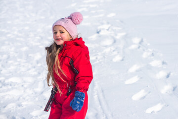 Child playing with snow in winter. Little girl in colorful knitted hat in winter park on Christmas. Kids play and jump in snowy forest.