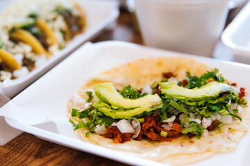 Al pastor tacos topped with avocados