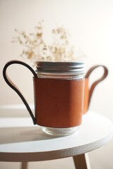 coffee mug on the white table , made from brown genuine leather