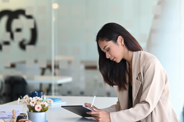 Side view of a confident businesswoman is working on tablet and sitting at her workspace.