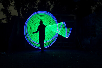 One person standing alone against a Colourful circle light painting as the backdrop