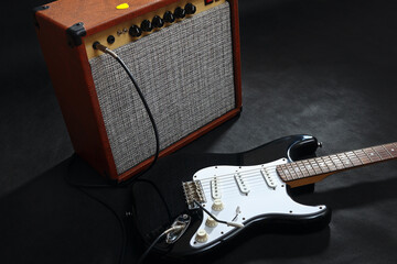 Brown guitar combo amplifier with black guitar on black background.