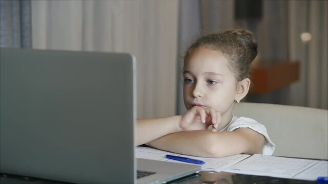The younger student sits at home at the computer, studies, listens to school lectures, and does his homework at home. Children at home, family education, children education concept.