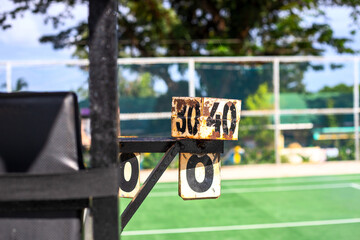 Rustic umpire chair with score counter on sunny tennis court. Simple public sport facility asset. Empty tennis court under sun concept photo. Public sport ban. Playing tennis in park. Score keeper