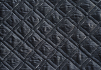 Grey quilted fabric background. Double machine stitching. Drawing in the form of squares