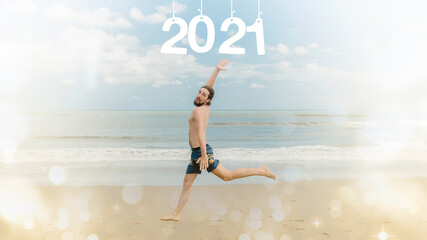 New Year concept. A man in shorts runs along the beach against the background of the sea. Inscription 2021