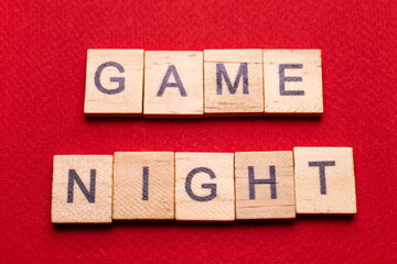 Wooden block lettering "Game night" on a red texture background: Board game background with space for text, minimalism