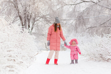 Fototapeta na wymiar mother and daughter in pink down jackets in winter